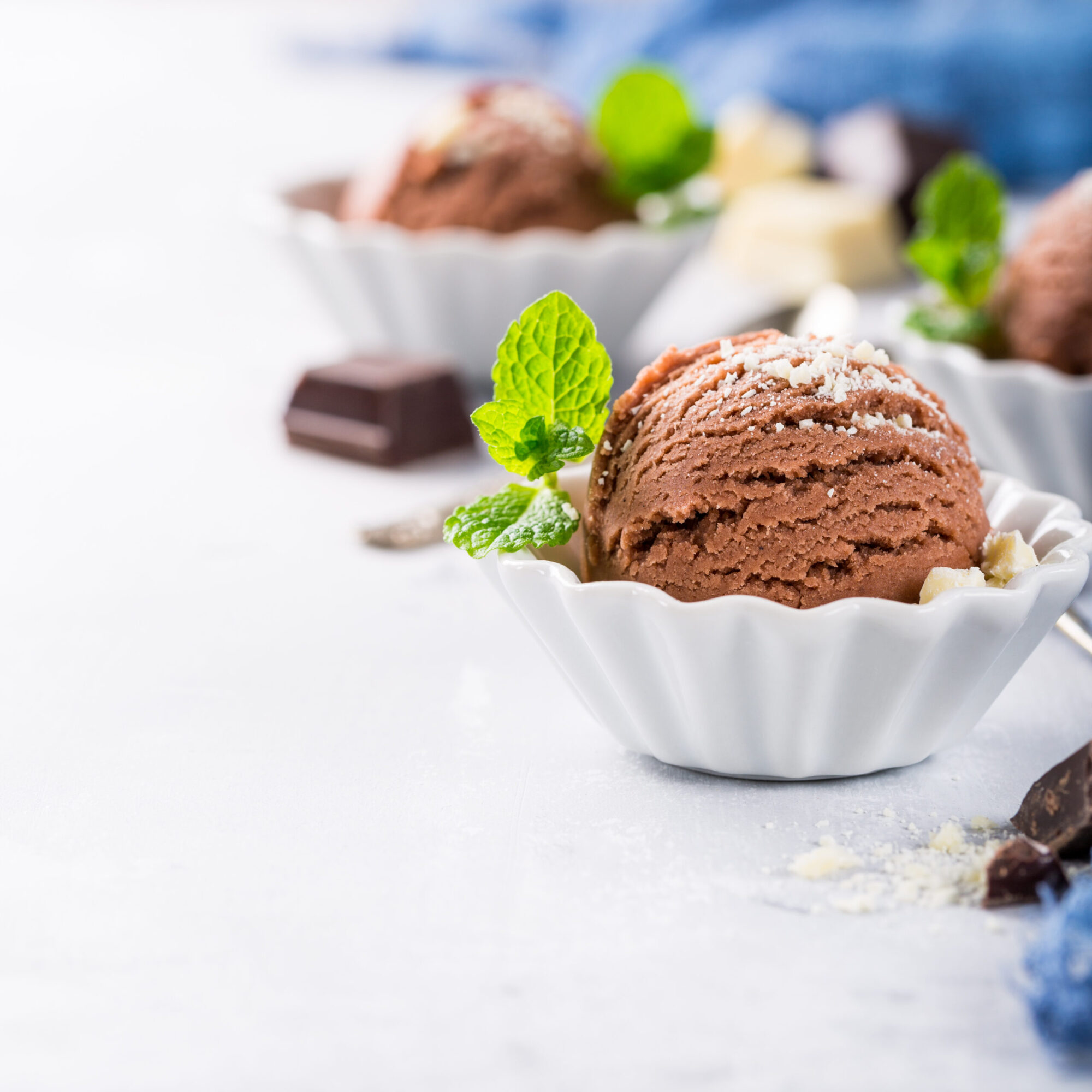 Chocolate ice cream in white bowl. Chocolate ice cream scoop in white bowl with chopped white chocolate and mint decoration. Summer food concept with copy space.